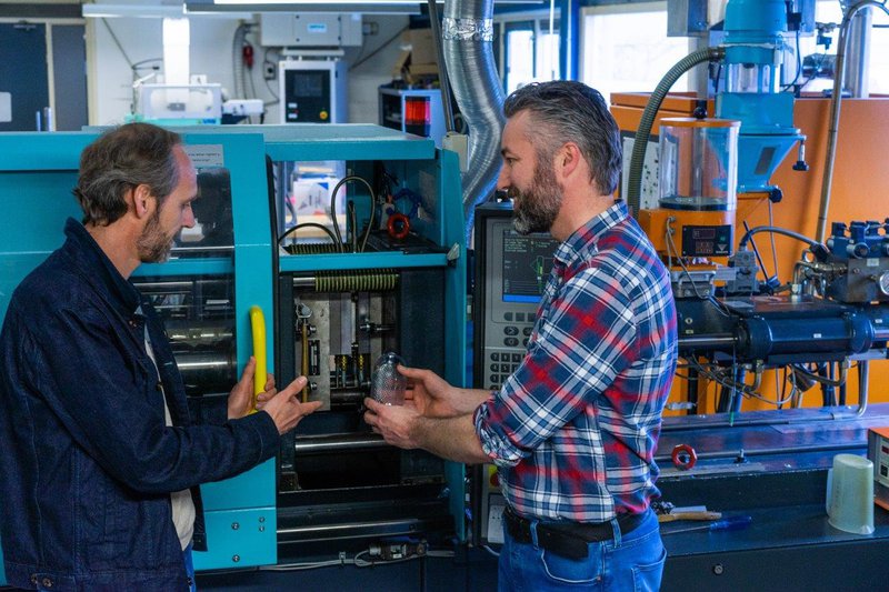 Arno Wolters (l) en Jelle Wijbrandi van Pezy bij de ESBM flessenblaasmachine, waarbij gebruik wordt gemaakt van mallen.